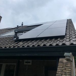 Een installatie van zonnepanelen op een hellend dak, zichtbaar zijn meerdere panelen en de dakbedekking.