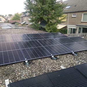 Een installatie van zonnepanelen op een plat dak, met meerdere panelen geplaatst op een grindbed.