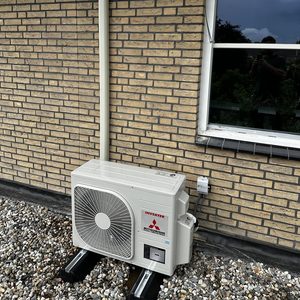De installatie toont een buitenunit van een airconditioningsysteem, duidelijk zichtbaar met de aansluitingen en de afvoerleiding.