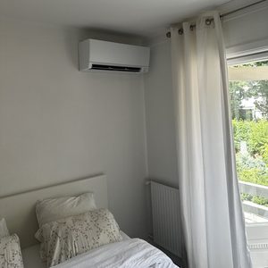 De afbeelding toont een wand-airconditioningsunit geïnstalleerd in een slaapkamer, ideaal voor koeling en verwarming.
