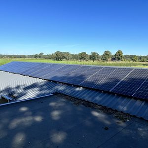 Een installatie van zonnepanelen op een hellend dak met uitzicht op groene velden.