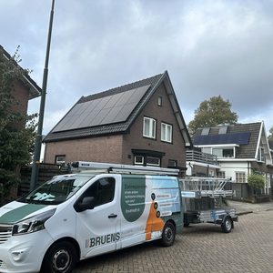 De foto toont een woning met zonnepanelen op het dak en een voertuig van het installatiebedrijf voor zonnepanelen.