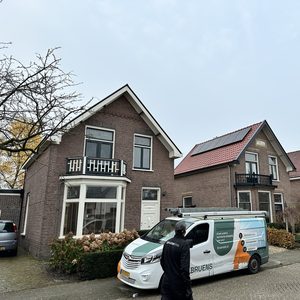 Een woning met zonnepanelen op het dak, geïnstalleerd tijdens een project. De installatie is zichtbaar vanaf de straat.