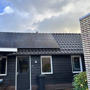 Een installatie van zonnepanelen op een schuin dak van een woning, met zichtbare zonnepanelen die energie opwekken.