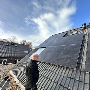 De installatie toont zonnepanelen op een schuin dak, met een werkende technicus die bezig is met de montage.