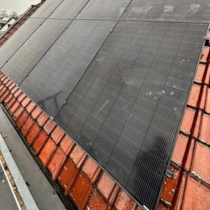 Installatie van zonnepanelen op een hellend dak. De panelen zijn goed zichtbaar en lijken recent geïnstalleerd.