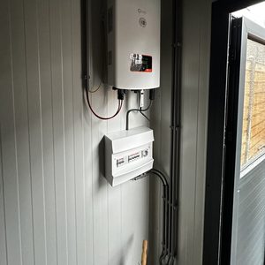 De afbeelding toont de omvormer van een zonnepaneleninstallatie, inclusief aansluitingen en een meterkast voor energiebeheer.