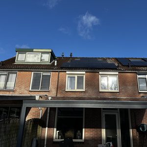 De foto toont een woning met zonnepanelen op het dak, typisch voor een duurzame energie-installatie.