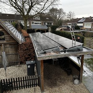 Installatie van zonnepanelen op een afdak, met een persoon die aan het werk is. De panelen zijn geplaatst voor optimale zonblootstelling.