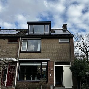 De afbeelding toont een woning met zonnepanelen op het dak, geïnstalleerd voor duurzame energieoplossingen.