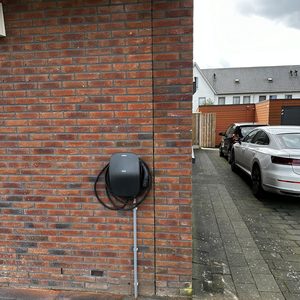 Een laadpaal voor elektrische voertuigen geïnstalleerd aan een stenen muur.