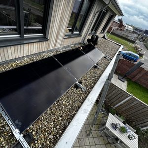 De afbeelding toont de installatie van zonnepanelen op een plat dak met een werknemer die aan het werk is.