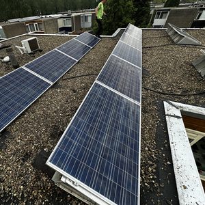 De installatie bestaat uit meerdere zonnepanelen op een platte dakoppervlakte, gericht op het opwekken van zonne-energie.