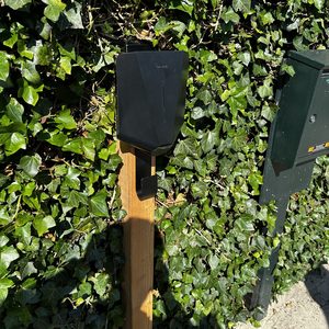 Een laadpaal voor elektrische voertuigen, bevestigd aan een houten paal, bevindt zich in een groene omgeving met veel klimop.