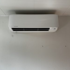 Een wandairconditioner is geïnstalleerd op een witte muur, met een schone en eenvoudige uitstraling.