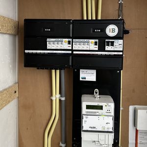 Een meterkast installatie met een digitale meter en verschillende schakelaars voor stroombeheer. De bedrading is netjes georganiseerd.