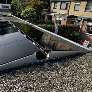 Deze afbeelding toont een installatie van zonnepanelen op een hellend dak, waarbij de panelen worden bevestigd en afgesteld.