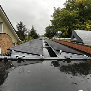 Installatie van zonnepanelen op een hellend dak, zichtbaar met montagebeugels en enkele panelen in een rechte lijn.