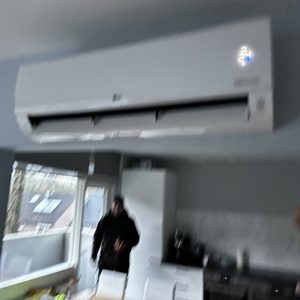 De afbeelding toont een wandunit van een airconditioning in een binnenomgeving, met het digitale display aan de voorkant zichtbaar.