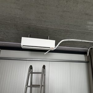 Deze afbeelding toont een wandairconditioner die net is geïnstalleerd, inclusief de leidingen die naar het apparaat leiden.