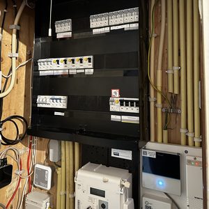 De afbeelding toont een meterkast met diverse elektrische componenten en bedrading, welke essentieel is voor de werking van een warmtepompinstallatie.