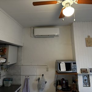 Een wandairco-installatie in een keukenruimte, geplaatst boven een keukentafel.