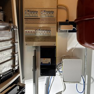 De afbeelding toont een meterkast met elektrische componenten en bekabeling voor de aansluiting van een laadpaal.