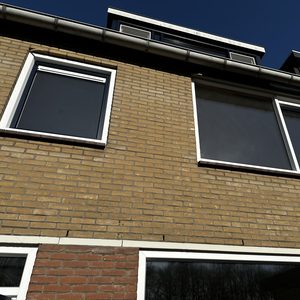 De afbeelding toont een deel van een gevel met ramen, zonder zichtbare elektrische systemen of installaties.