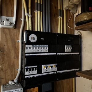 Een meterkast met verschillende schakelaars en kabels, die essentieel is voor het beheer van elektriciteit in een woning.