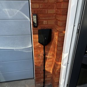 Deze afbeelding toont een laadpaal voor elektrische voertuigen, bevestigd aan de muur van een huis.