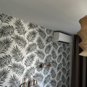 De afbeelding toont een wandairco-installatie in een modern ingericht interieur met een bloemenmotief op de muur.