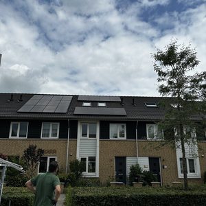 De foto toont een woning met zonnepanelen op het dak, wat wijst op een hernieuwbare energie-installatie.