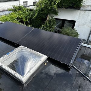 De foto toont zonnepanelen geïnstalleerd op een plat dak, met een licht reflecterende oppervlakte en omliggende vegetatie.
