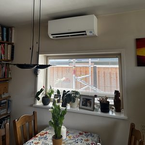 De afbeelding toont een geïnstalleerde airconditioner aan de muur in een binnenruimte, met een mooi interieur op de achtergrond.