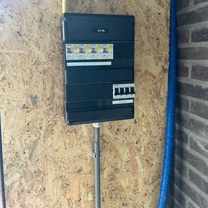 Een netwerkkast met meerdere stroomonderbrekers, geïnstalleerd op een wand met houten panelen, ideaal voor het beheren van elektriciteitsvoorzieningen.