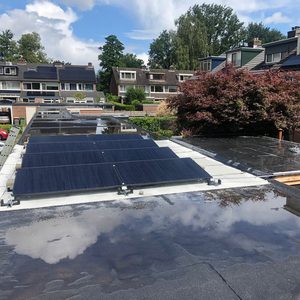 De installatie toont een set zonnepanelen op het dak, met reflectie van de lucht en omgeving op het oppervlak.