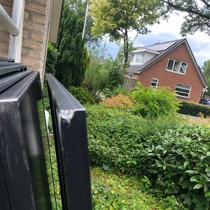 Deze afbeelding toont zonnepanelen die klaar zijn voor installatie. De panelen staan opgesteld naast een woning, met een groene omgeving.