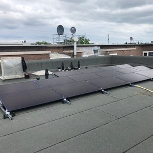 Deze afbeelding toont een installatie van zonnepanelen op een plat dak, met meerdere panelen goed zichtbaar en verbonden met de ondergrond.