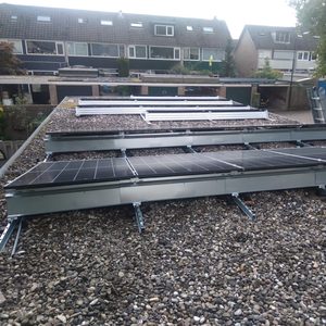De installatie toont zonnepanelen die op een dak zijn gemonteerd met metalen steunen en grindbedekking.