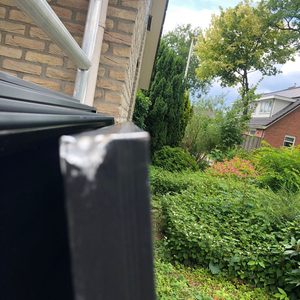 De installatie bestaat uit zonnepanelen die zijn bevestigd op een hellend dak, met een zicht op de omgeving met groenere vegetatie.
