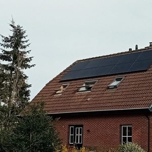 De installatie toont een huis met zonnepanelen op het schuine dak. De panelen zijn goed zichtbaar en zijn gericht op het zuiden voor optimale zoninname.