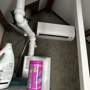 Deze installatie toont een airco-systeem met een binnenunit en bijbehorende afvoerpijpen in een ruimte.