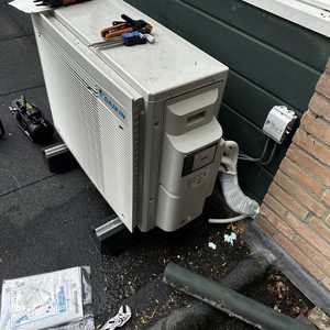 Een buitenunit van een airconditioningsysteem, compleet met gereedschap en installatie-instructies in de buurt.
