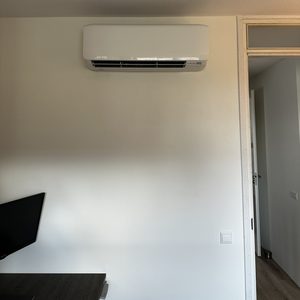 Een wandgemonteerde airconditioner is geïnstalleerd in een interieur, biedt koeling en comfort.