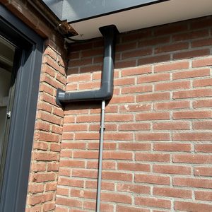 De installatie toont een afvoerpijp voor een airconditioningseenheid die aan de wand is bevestigd.