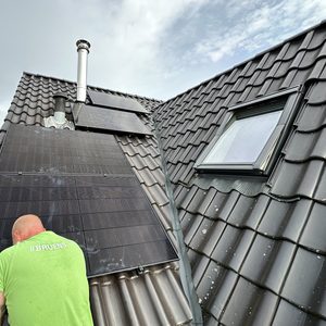 Een installateur plaatst zonnepanelen op een hellend dak, gericht op het benutten van zonne-energie.