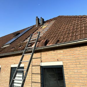 De foto toont een dak waar zonnepanelen worden geïnstalleerd, met een ladder die naar het dak leidt.