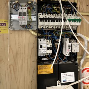 De afbeelding toont een meterkast met verschillende elektrische installaties en bedrading, nuttig voor de bediening van zonnepanelen.
