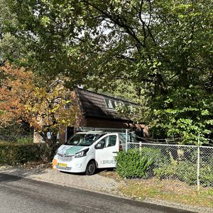 De afbeelding toont een huis met zonnepanelen op het dak en een installatievoertuig voor zonnepanelen in de nabijheid.