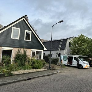 De foto toont een woning met een lopende installatie van zonnepanelen op het dak, met een vrachtwagen voor de werkzaamheden.